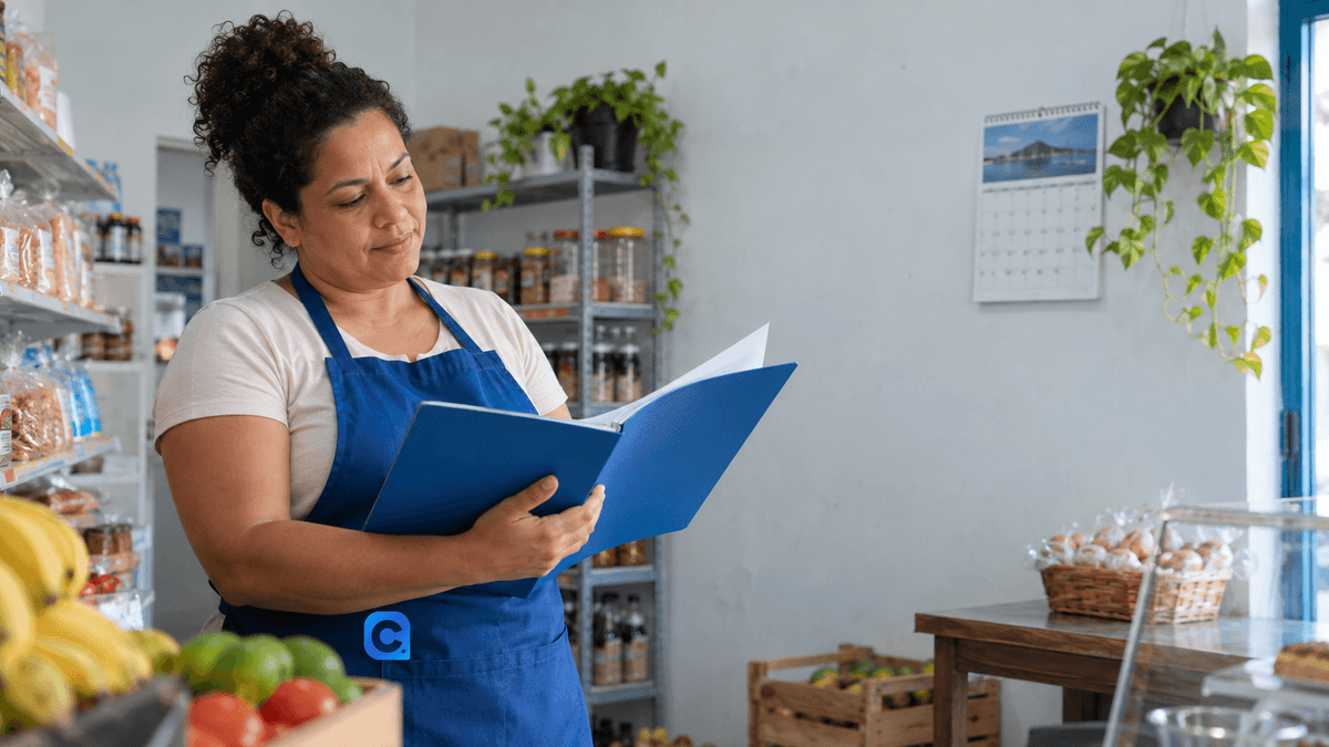 Comerciante confere documentos e calendário em seu pequeno estabelecimento.
