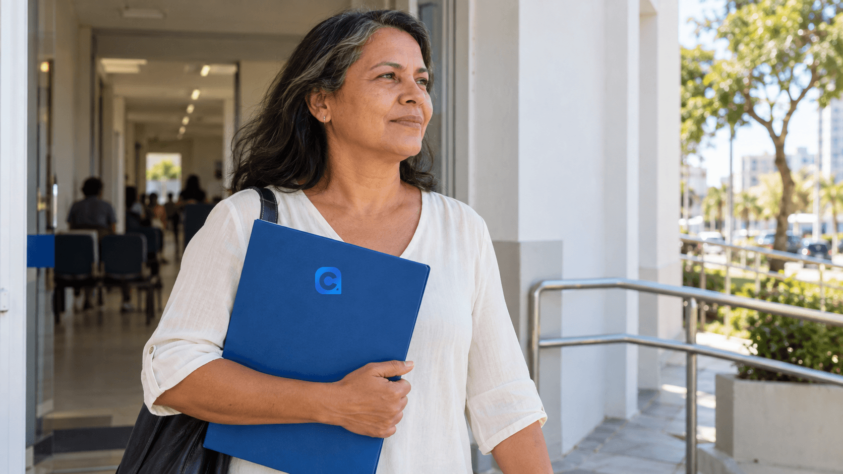 Mulher segurando pasta azul com símbolo Meu Consig em entrada de edifício de atendimento.