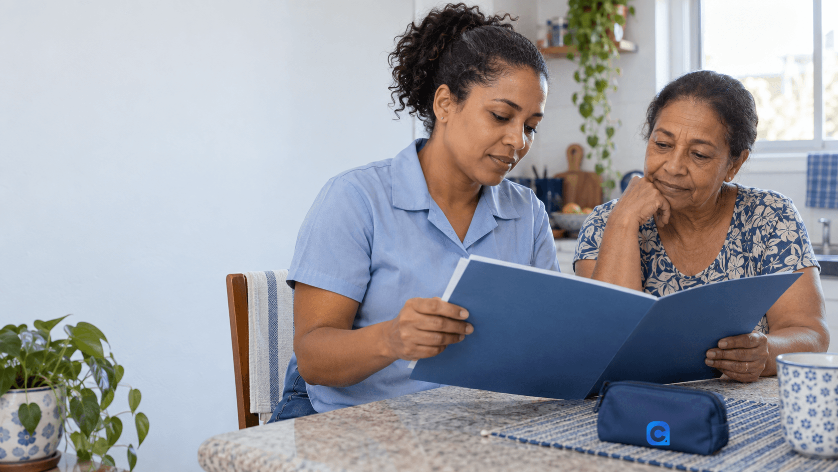 Duas mulheres adultas consultam juntas documentos sobre uma mesa em casa; o símbolo Meu Consig aparece em um estojo azul.