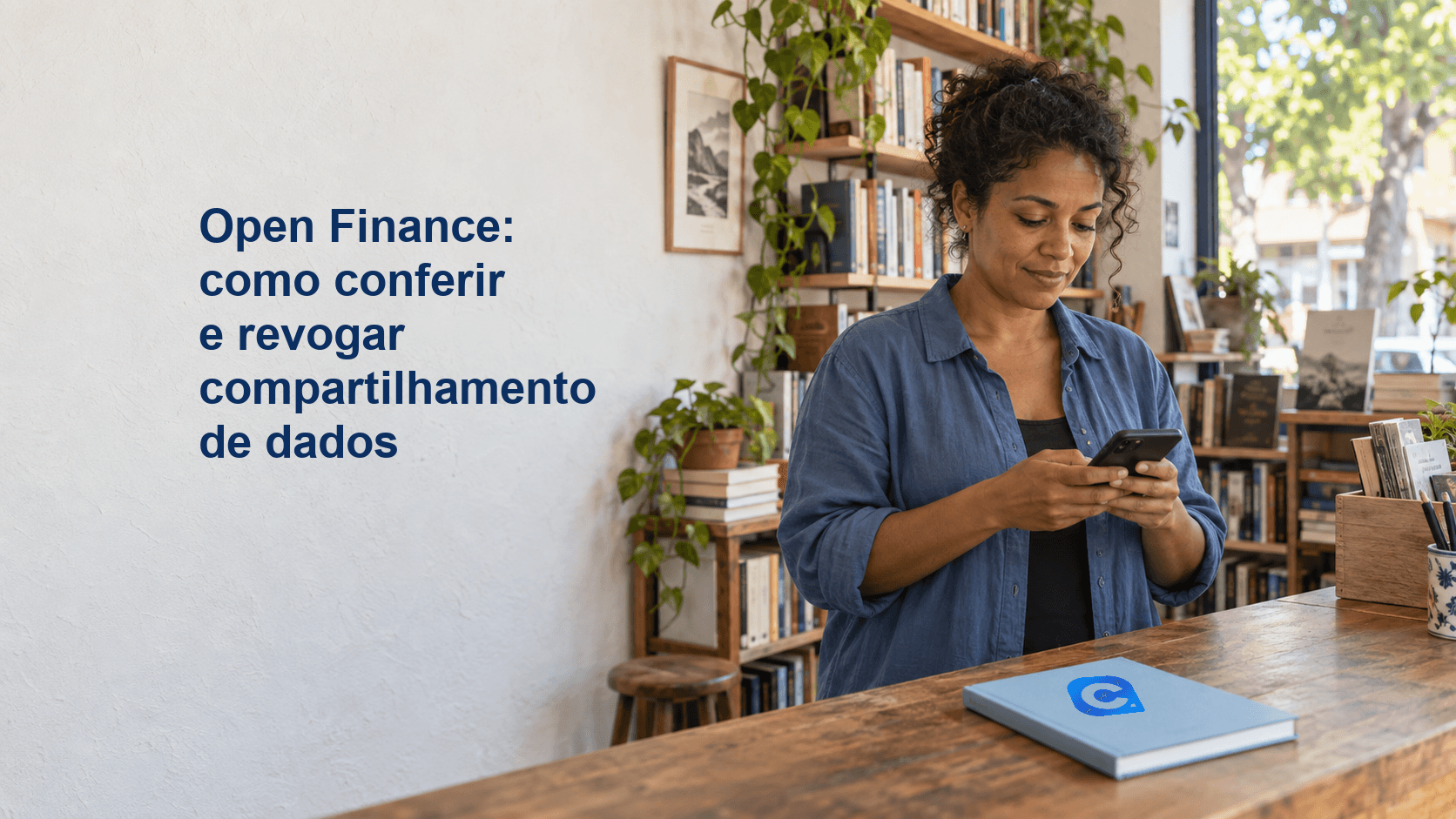 Livreira confere o celular atrás do balcão de uma livraria, com caderno claro marcado pelo símbolo Meu Consig.